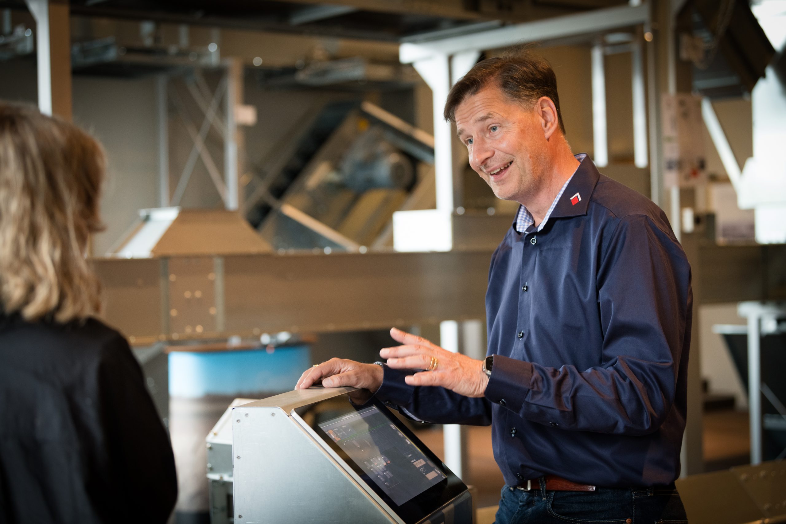 A man is standing at a computer screen talking to a woman.