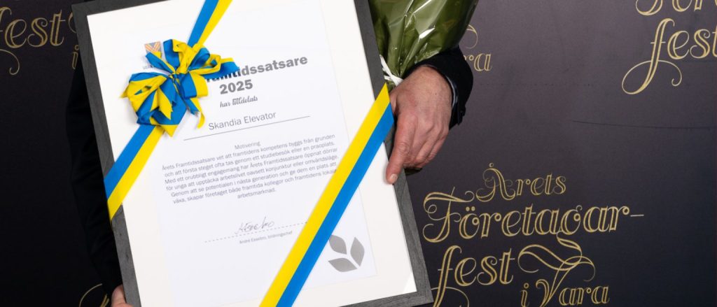 Person holding an official certificate and flower bouquet.